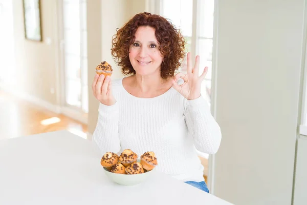 Senior Woman Eating Chocolate Chips Muffins Doing Sign Fingers Excellent — Stock Photo, Image