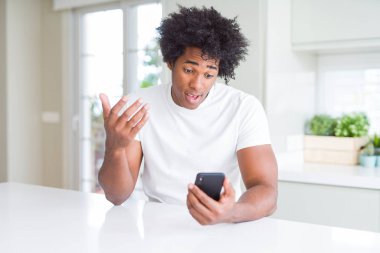 Bir sürpriz yüz, korkuyor ve heyecanlı korku ifadesi ile Smartphone şokta korktuğunu kullanan Afrikalı-Amerikalı adam