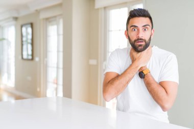 Evde yakışıklı İspanyol adam rahat beyaz t-shirt çığlık ve ağrılı boğma çünkü boğulmak. Sağlık problemi. Asphyxiate ve intihar konsepti.