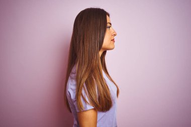 Genç güzel kadın rahat t-shirt ayakta izole pembe arka plan tarafına bakıyor giyen, profil rahat bir gülümseme ile doğal yüz ile poz Relax.