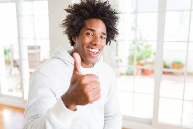 Afrikalı Amerikalı adam el ile jest kadar mutlu thumbs yapıyor Sweatshirt giyiyor. Başarı gösteren kameraya bakarak ifadeyi onaylama.