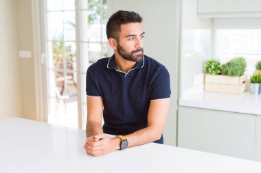 Evde yan arayan yakışıklı İspanyol adam, güvenli bir gülümseme ile doğal yüz ile profil poz rahatlayın.