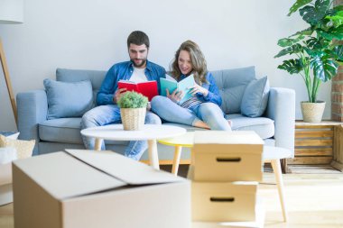 Genç çift kanepede bir kitap okuma rahatlatıcı, yeni bir eve hareket için bir mola alarak