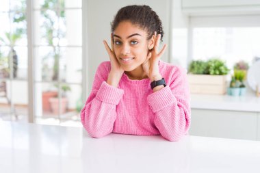Güzel African Amerikan kadın ile afro saç giyen Casual pembe kazak iki elini de kulak jestinde duymaya çalışıyorum, dedikoduyu merak ediyor. İşitme sorunu, sağır