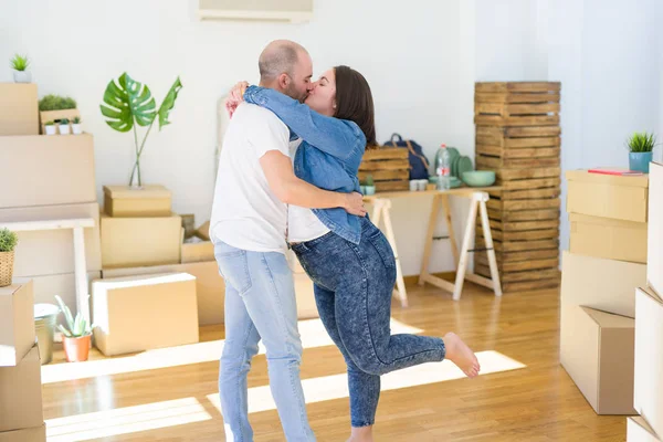 Junges Paar umarmt sich verliebt in Kartons im neuen Zuhause, — Stockfoto