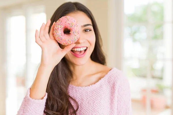 目にピンクのドーナツを見て笑っている美しい若い女性 — ストック写真