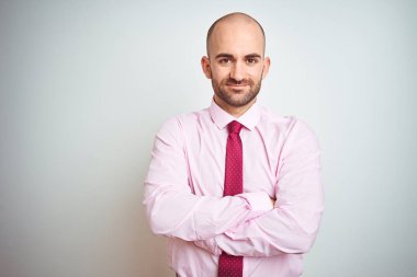 İzole arka plan üzerinde pembe kravat giyen genç iş adamı kamera bakıyor çapraz silah ile gülümseyen yüz. Pozitif kişi.