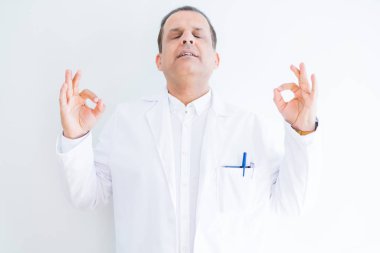 Orta yaş Doktor adam beyaz arka plan üzerinde tıbbi ceket giyiyor Relax ve gözleri ile gülümseyen meditasyon jest parmaklar ile kapalı. Yoga konsepti.