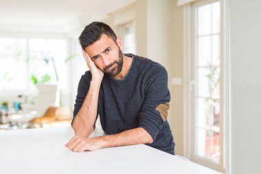 Evde düşünme seyir yorgun ve çapraz kolları olan depresyon sorunları ile sıkılmış rahat kazak giyen İspanyol yakışıklı.