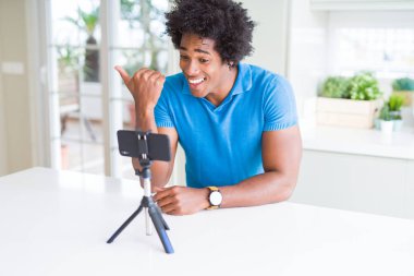 Afrikalı Amerikan adam web kamerası ile akıllı telefon işaret ve mutlu yüz gülümseyen yan başparmak ile gösteren kullanarak online çağrı yapıyor