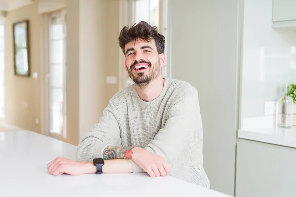 Joven guapo sonriendo alegre a la cámara con cruzado un — Foto de Stock