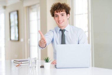 Ofis bilgisayar laptop ile çalışan genç iş adamı tebrik ve davetkar olarak dost sunan el sıkışması gülümseyen. Başarılı iş.