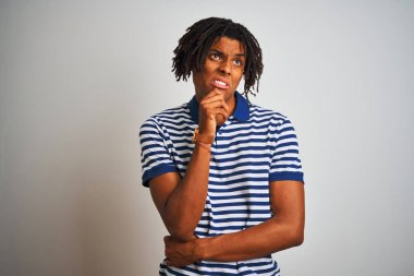Beyaz arka plan üzerinde ayakta çizgili mavi polo giyen dreadlocks ile Afro adam bir soru hakkında endişeli düşünme, çene el ile ilgili ve gergin