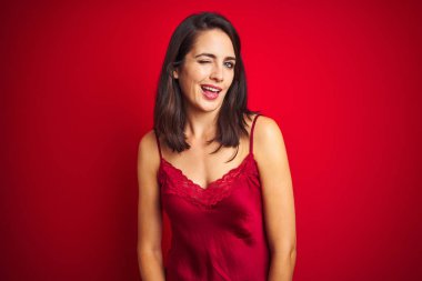 Seksi ifade, neşeli ve mutlu yüz ile kamera bakarak kırmızı izole arka plan üzerinde seksi iç çamaşırı giyen genç güzel kadın.