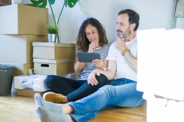 Orta yaş Senior çift yeni bir eve tablet ciddi yüz soru hakkında düşünme kullanarak hareket, çok karışık fikir