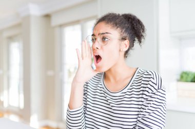 Bağırarak ve ağzı üzerinde el ile yan için çığlık gözlüklü afro saçlı güzel genç Afro-Amerikan kadın. İletişim kavramı.