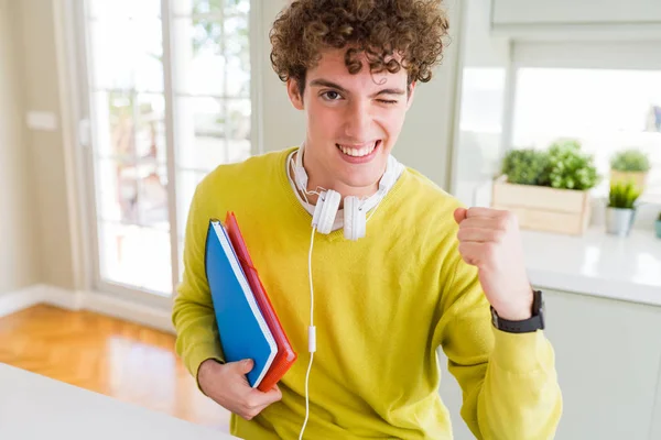 ヘッドフォンを着用し 誇りを叫ぶノートを持っている若い学生の男は 非常に興奮し 歓声の感情を祝う — ストック写真