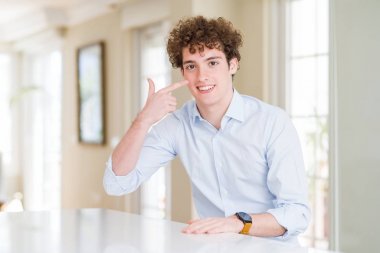 Kıvırcık okuma kafası ile genç iş adamı yüz ve burun, neşeli gülümseyen el parmağı ile Işaret. Güzellik konsepti