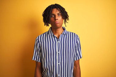 Issız sarı arka plan üzerinde rahat çizgili t-shirt giyen dreadlocks ile Afro adam depresif ve sıkıntı için endişe, ağlayan öfkeli ve korkuyor. Üzücü ifade.