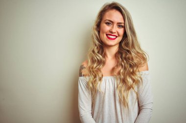 Genç güzel kadın yüzünde mutlu ve serin bir gülümseme ile beyaz izole arka plan üzerinde ayakta. Şanslı kişi.