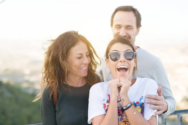 Семья из трех улыбающихся веселых веселых, веселых на открытом воздухе — стоковое фото