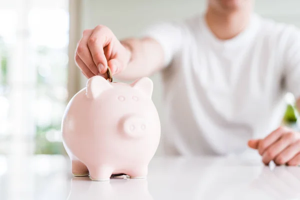 Close up van de man brengen van een munt binnen piggy bank als sparen of in — Stockfoto