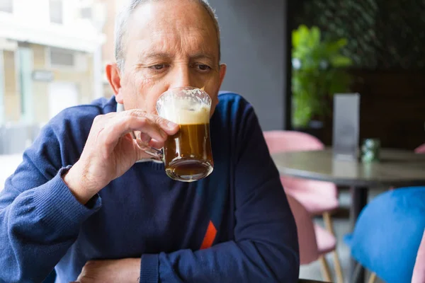 Красивый мужчина среднего возраста, пьющий кофе в ресторане, с — стоковое фото