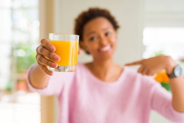 Genç Afrikalı Amerikalı kadın kendini sürpriz yüz işaret parmak ile evde portakal suyu elsanatı