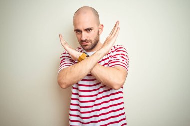 Beyaz izole arka planda rahat çizgili kırmızı t-shirt giyen sakal ile genç kel adam ret ifadesi geçiş kolları negatif işareti, öfkeli yüz yapıyor