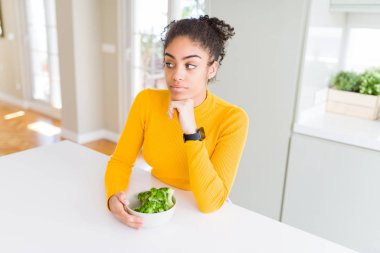 Genç African Amerikan Kız yeme heatlhy yeşil brokoli ciddi yüz düşünme hakkında soru, çok karışık fikir