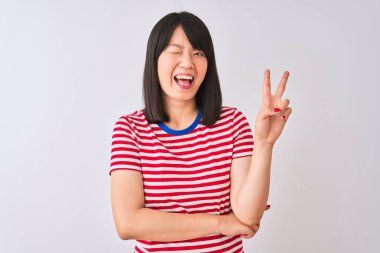 Genç güzel Çinli kadın kırmızı çizgili t-shirt üzerinde izole beyaz arka plan ile gülümseyen mutlu yüz siyah parmak ile zafer işareti yapıyor kamera göz kırpıyor. İki numara.