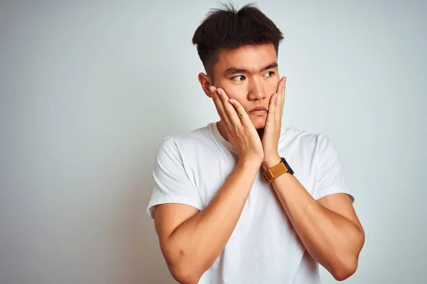 孤立した白い背景の上に立つTシャツを着た若いアジアの中国人男性は うつ病と悲しみを覆う疲れた手 動揺と問題のためにイライラ — ストック写真