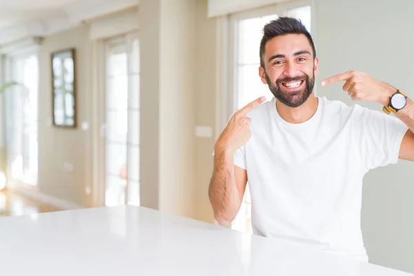 ハンサムなヒスパニックの男カジュアルな白いTシャツは 自信を持って示し 指の歯と口で指差し笑顔 健康の概念 — ストック写真