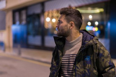 Yakışıklı delikanlı possing ve gülümseyerek. Geceleri sokak stili