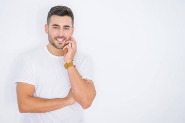 Beyaz izole arka plan üzerinde rahat beyaz t-shirt giyen mutlu gülümseyen genç yakışıklı adam