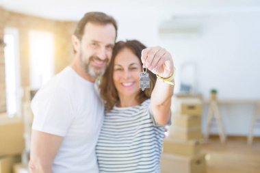 Middle age senior romantic couple holding and showing house keys clipart