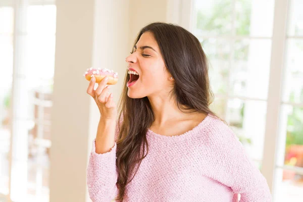 Młoda piękna kobieta jedząca smaczny różowy pączek — Zdjęcie stockowe