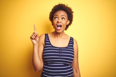 Beauitul Afrikalı Amerikan kadın izole sarı arka plan üzerinde yaz t-shirt giyen başarılı bir fikir ile parmak yukarı işaret. Çıkıldı ve mutlu. Bir numara.
