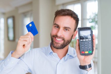 POS terminal tutan yakışıklı iş adamı ve kredi kartı, satın alma ve dataphone ile ödeme