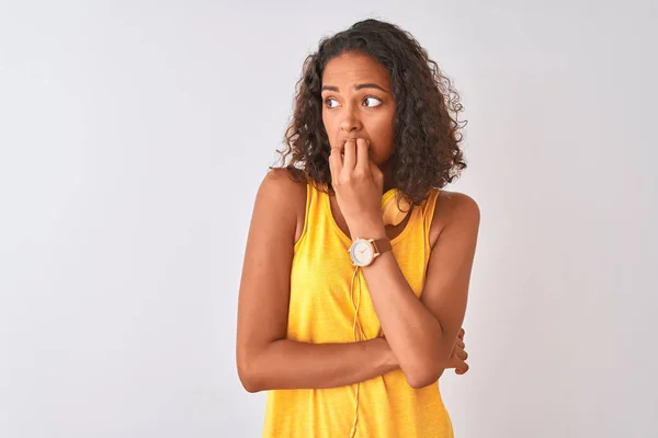 年轻的巴西妇女戴着黄色耳机在孤立的白色背景看起来紧张和紧张与手的嘴咬指甲 焦虑问题 — 图库照片