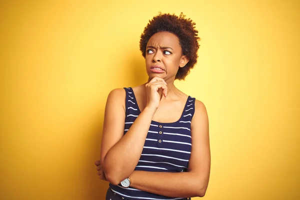 Beauitul african american woman wearing summer t-shirt over isolated yellow background Thinking worried about a question, concerned and nervous with hand on chin