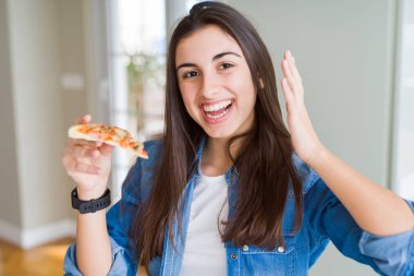 Güzel genç kadın lezzetli pizza çok mutlu ve heyecanlı bir dilim yeme, kazanan ifade zafer büyük gülümseme ve yükseltilmiş eller ile çığlık kutluyor