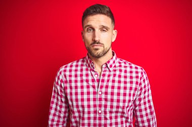 Genç yakışıklı adam üzerinde kırmızı izole arka plan görünümlü uykulu ve yorgun, yorgunluk ve akşamdan kalma için yorgun, sabah tembel gözleri.