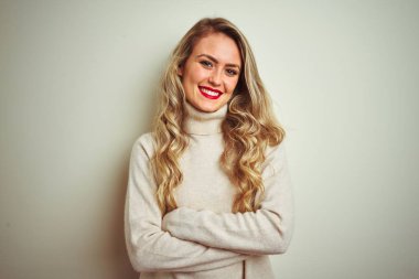 Izole beyaz arka plan mutlu yüz üzerinde kış boğazlı kazak giyen güzel kadın kameraya bakarak çapraz kolları ile gülümseyerek. Pozitif kişi.