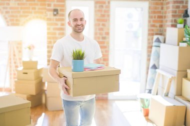 Genç yakışıklı adam yeni bir eve hareket, cardboxes SMIL tutarak