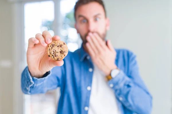 Bonito Homem Comendo Biscoitos Chocolate Cobrir Boca Com Mão Chocada — Fotografia de Stock