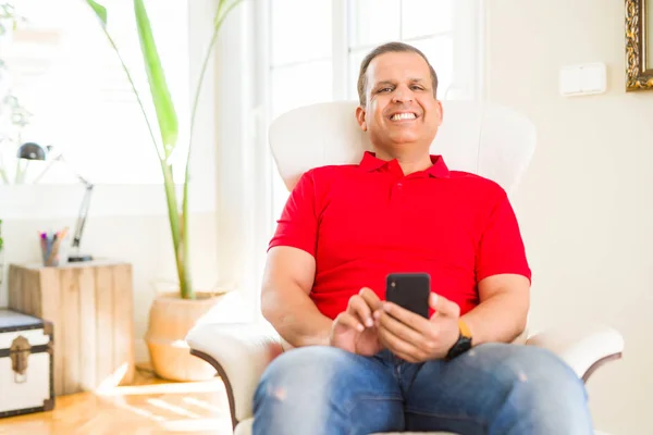 Hombre de mediana edad sonriendo alegre blanco usando teléfono inteligente sentado o —  Fotos de Stock