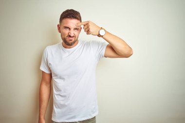 İzole arka planda rahat beyaz t-shirt giyen genç yakışıklı adam alnında sivilce mutsuz işaret, siyah kafa çirkin enfeksiyon. Akne ve cilt sorunu