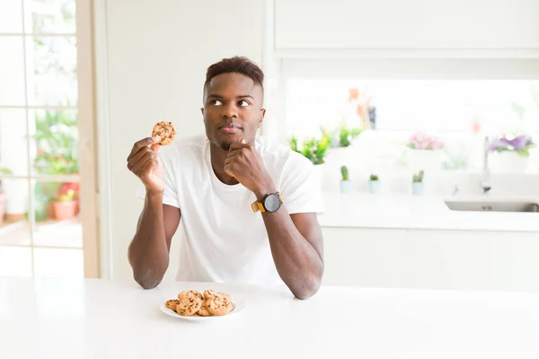 Mladý Afričan Americký Muž Pojídáním Čokoládových Chipsů Sušenky Vážný Obličej — Stock fotografie