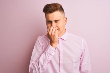 Genç yakışıklı işadamı izole pembe arka plan üzerinde duran zarif gömlek giyen stresli ve ağız tırnakısırma elleri ile sinirli görünümlü. Anksiyete sorunu.